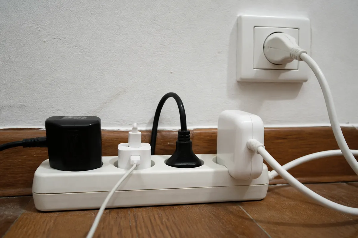 Regleta doméstica con varios enchufes ocupados junto al zócalo